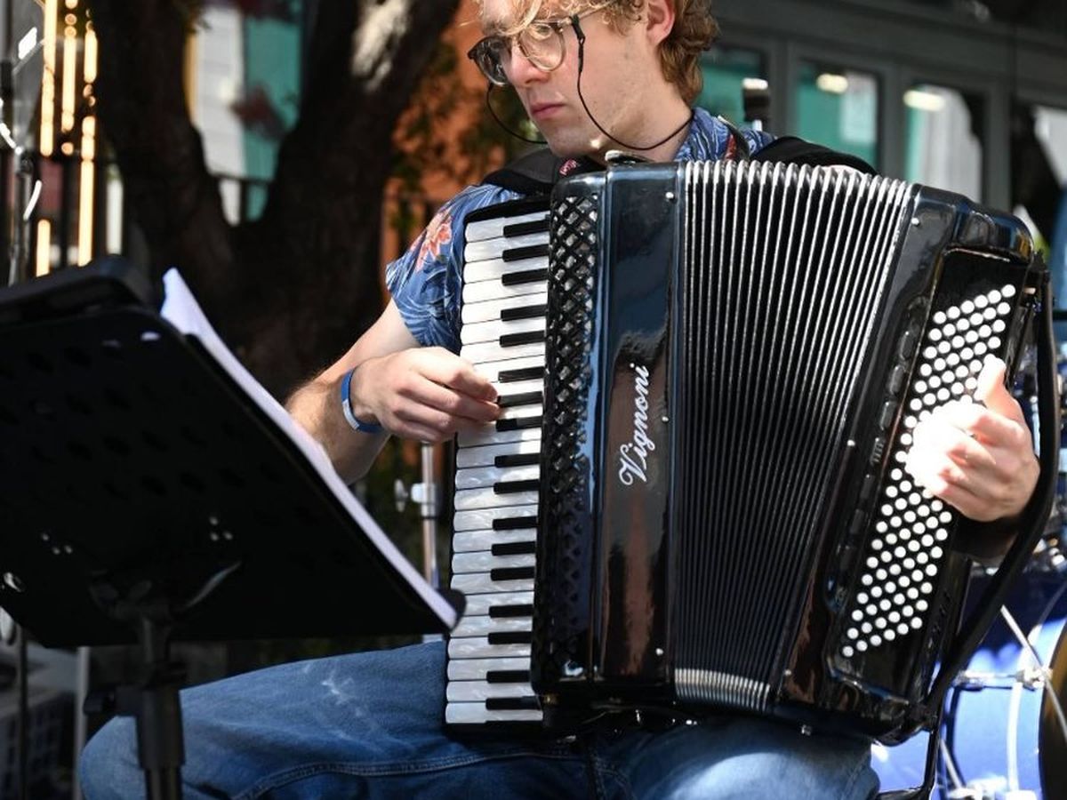 An accordionist performing on stage in the sunshine