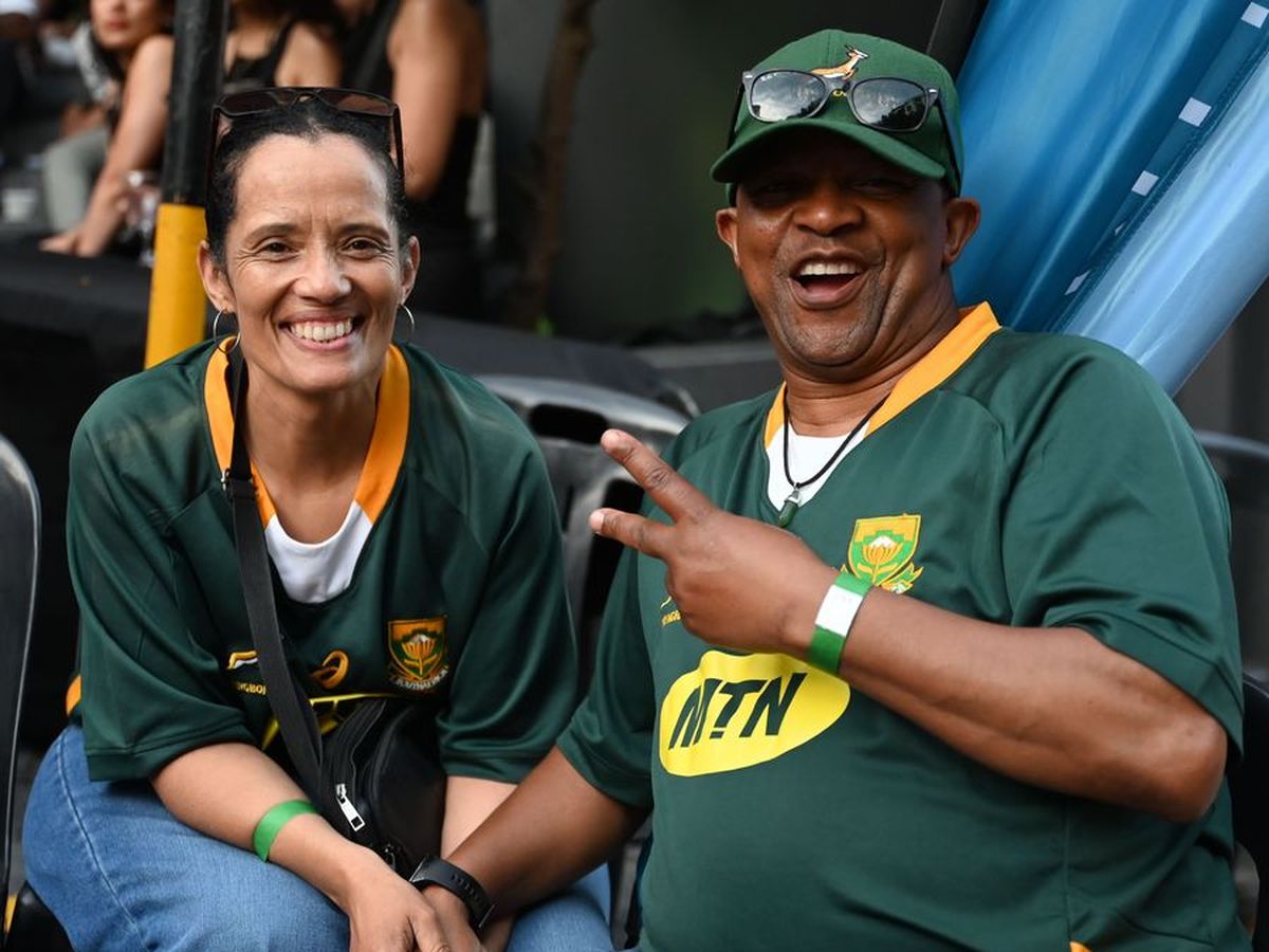 Two supporters in Springbok jerseys smiling at a festival table