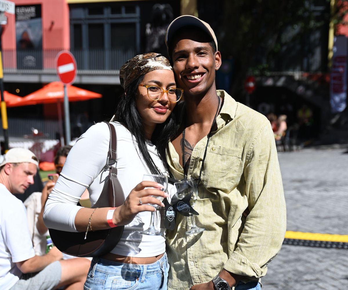 Two festival-goers holding branded Italy in Town tasting glasses on lanyards