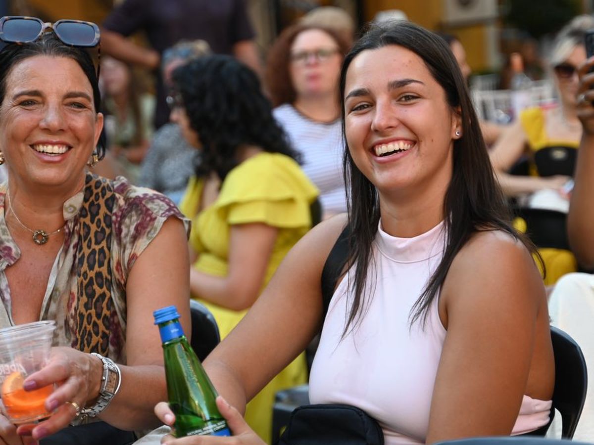 Two friends laughing together at a table with drinks