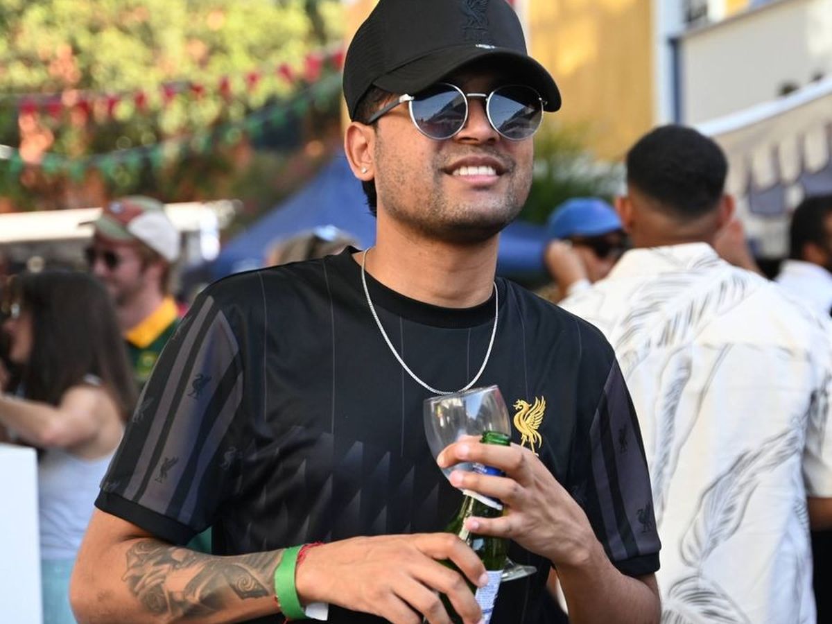 A festival-goer holding a wine glass and a bottle in the crowd