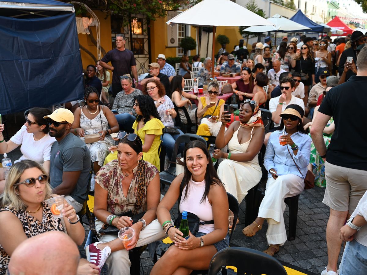 Festival-goers seated with Aperol spritzes in the afternoon sun