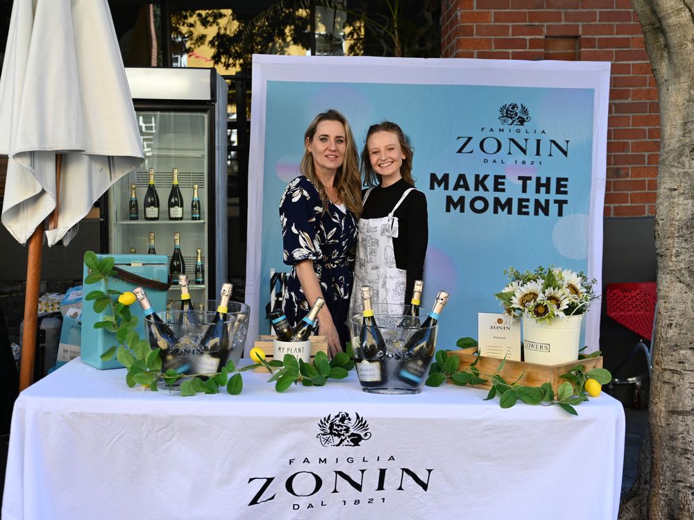 A sparkling wine brand stand with a branded backdrop and chilled bottles
