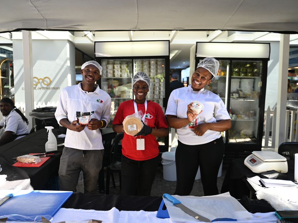 Cheesemakers holding fresh mozzarella and burrata at their counter