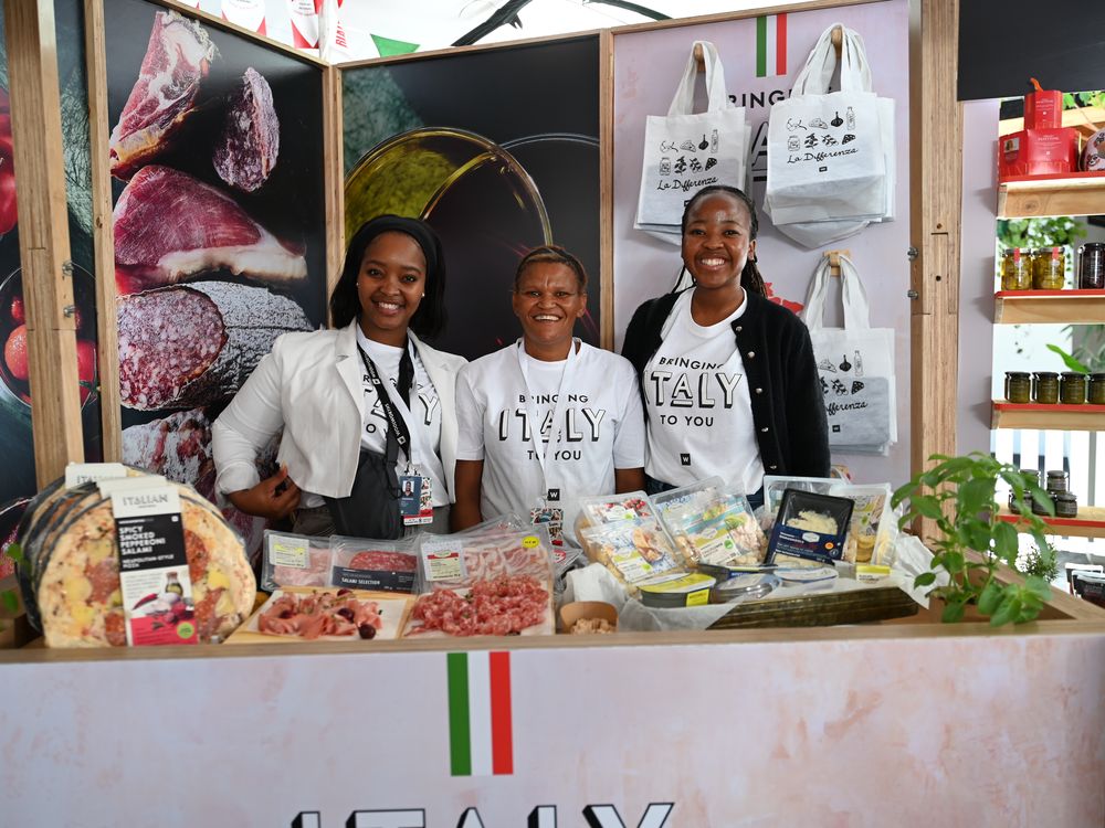 A retail team at a stand stocked with Italian deli products and branded totes