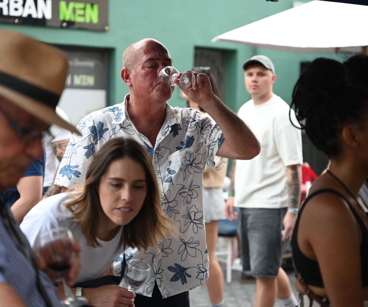 A festival-goer tasting a glass of wine in the crowd